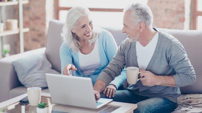 Zwei Menschen sitzen vor dem Computer und lächeln