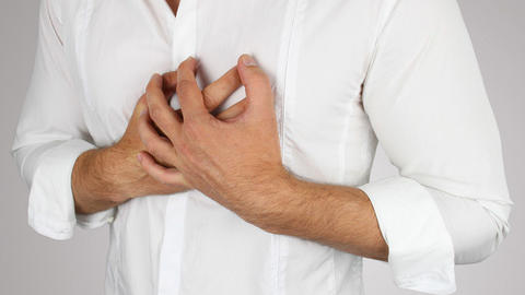 Mann fasst sich an die Brust