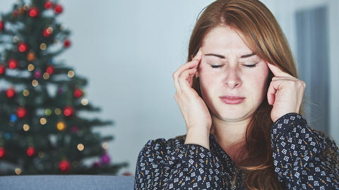 Frau fasst sich mit beiden Händen an den Kopf, im Hintergrund ist ein Weihnachtsbaum