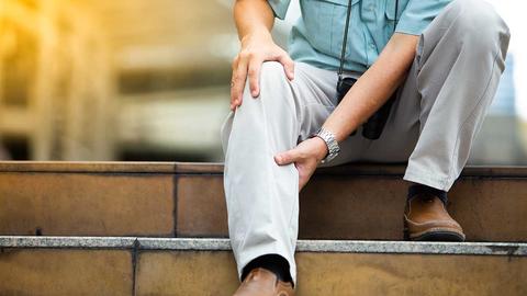 Man sitzt auf der Treppe und hat Beinschmerzen - Warnsignal für pAVK