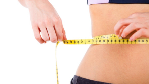 Bild von einer Frau, die sich mit dem Maßband den Taillenumfang misst