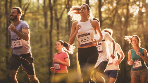 Frau läuft mit anderen Personen einen Marathon im Wald